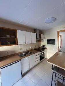 a kitchen with white cabinets and a table in it at Vacaciones en la playa in Sant Carles de la Ràpita +2 photos