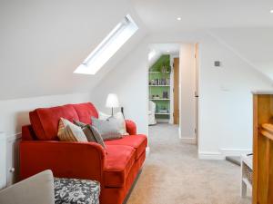 a living room with a red couch with pillows at Cartwheel Cottage in Hayton
