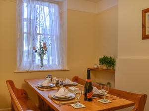 tavolo da pranzo con una bottiglia di vino e una finestra di Waterside Cottage a Saltash