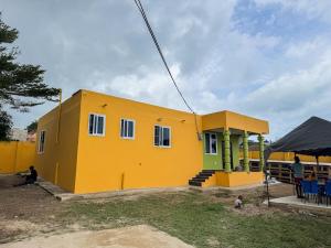 a yellow house with a man standing in front of it at Kayemville in Kasoa
