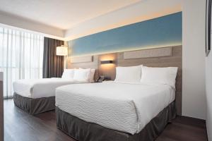 two beds in a hotel room with white pillows at Holiday Inn Express Guadalajara Expo by IHG in Guadalajara
