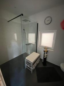 a bathroom with a shower and a clock on the wall at Ferienwohnung Fiss Dorfhain  +9 photos
