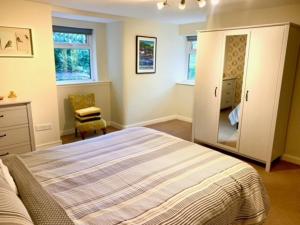 a bedroom with a bed and a dresser and a mirror at Outstanding Llangollen Riverside Apartment in Llangollen