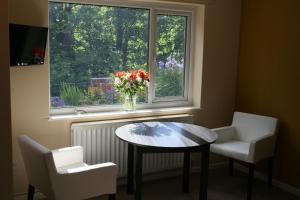 a table and two chairs and a vase of flowers in a window at Outstanding Llangollen Riverside Apartment in Llangollen