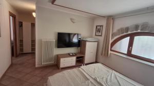 una camera da letto con un letto, una tv e una finestra di La Bella Corte ad Arco