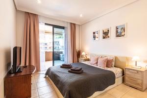 a bedroom with a bed and a tv and a window at Top Floor Ocean View Apt By Dream Homes Tenerife in Puerto de Santiago
