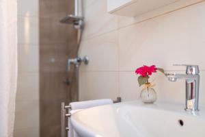 a bathroom sink with a vase with a red flower in it at Apartment Milka in Krk