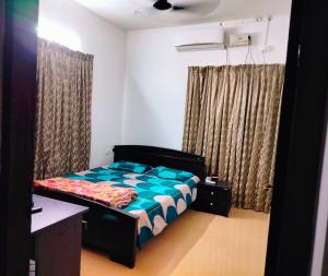 a bedroom with a bed and a desk and curtains at Gripzy Serene Abode-Kazhakuttam in Trivandrum
