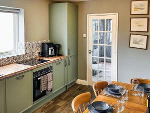 a kitchen with green cabinets and a table with chairs at Heath View in Saxmundham +9 photos