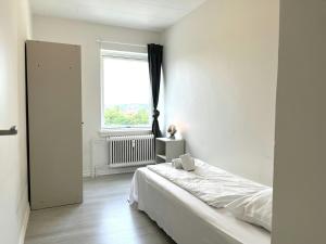 a white bedroom with a bed and a window at Spacious Apartment for 4 in Aalborg