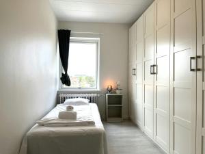a white bedroom with a bed and a window at Spacious Apartment for 4 in Aalborg +4 photos
