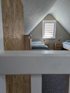 a attic room with two beds and a window at Domek Letniskowy Zefirek in Nowy Dwór