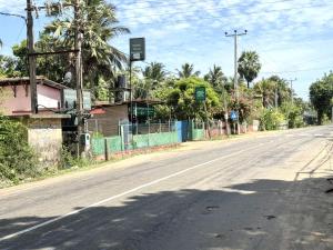Una calle vacía con árboles y una valla al costado. en Holiday In Nilaveli Resort, en Trincomalee 1 foto más