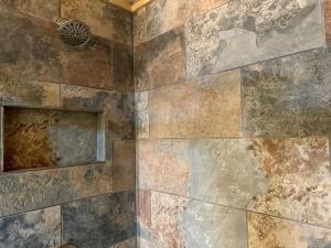ein Bad mit einer Dusche und einer Steinmauer in der Unterkunft Laurelwood Luxury Cabin Hot Tub in Cosby + 42 Fotos