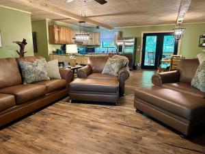 ein Wohnzimmer mit Ledersofas und eine Küche in der Unterkunft Laurelwood Luxury Cabin Hot Tub in Cosby