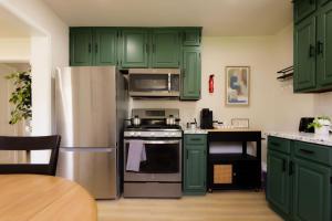 een keuken met groene kasten en een roestvrijstalen koelkast bij Heights Haven on Paris - 2BD Stay in Peoria Heights