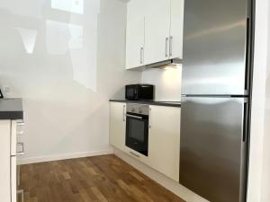 a kitchen with white cabinets and a stainless steel refrigerator at Spacious Apartment for 8 in Eternitten in Aalborg