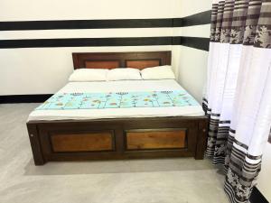 Un dormitorio con una cama con marco de cama de madera. en Holiday In Nilaveli Resort, en Trincomalee