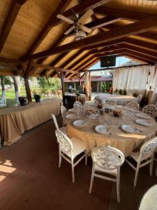a large wooden table with white chairs and a ceiling at Gigios Sport&Relax in Băileşti