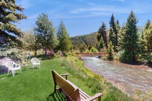 two benches sitting on the grass next to a river at Snowdance Condo A101 in Keystone