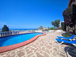 a swimming pool with lounge chairs and the ocean at Alturas del Montgo in Denia