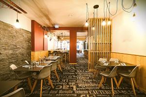 ein Restaurant mit Tischen und Stühlen und einer Backsteinmauer in der Unterkunft Le Sacca Hôtel restaurant in Cauterets