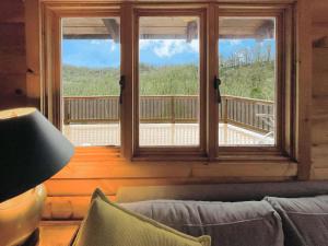a living room with a couch and a large window at Log Cabin w Fireplace, EV Station & River Access in Great Cacapon +38 photos