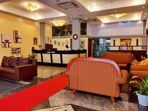 a lobby with leather chairs and a bar in the background at Hotel Nikko Towers in Dar es Salaam