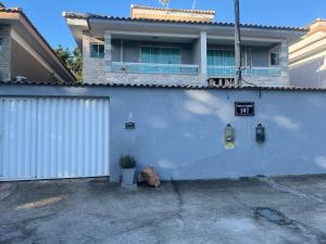 a house with a blue wall with a plant next to it at Conforto Perto da Praia in Cabo Frio
