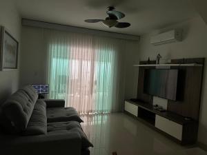 a living room with a couch and a television at Conforto Perto da Praia in Cabo Frio