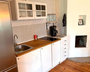 a small kitchen with white cabinets and a sink at Drängstugan - Tiny House in Johannesberg