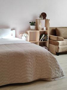 a bedroom with a bed and a couch and a chair at Однокімнатна на Троєщині in Kyiv