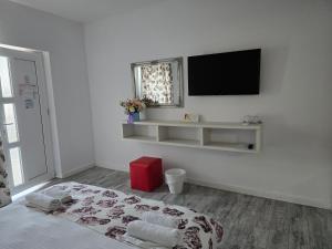 a white room with a bed and a television on a wall at Anacris Guesthouse in Costinesti +40 photos