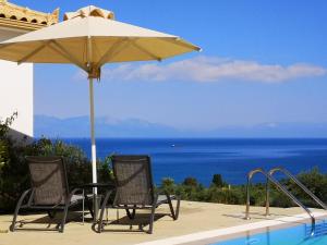 two chairs and an umbrella next to a swimming pool at The Iconpainter Kalamaki Villa in Kómboi