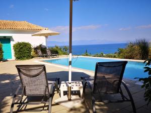 two chairs and an umbrella next to a swimming pool at The Iconpainter Kalamaki Villa in Kómboi