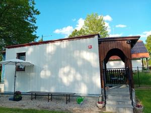 a white shed with a bench and an umbrella at Chata Srlín in Bernartice