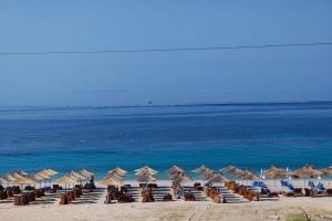 a beach with chairs and umbrellas and the ocean at Anxhelos Hotel in Himare