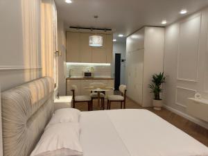 a bedroom with a white bed and a kitchen at NBG d 'amore Appart in Batumi