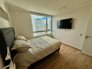 Un dormitorio con una cama y una ventana grande. en Nuevo y cómodo en Costa de Montemar, en Concón