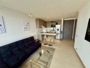 Una sala de estar con un sofá y una cocina. en Nuevo y cómodo en Costa de Montemar, en Concón