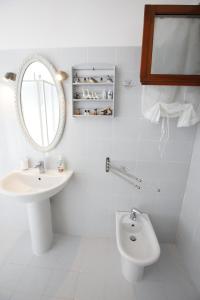 a white bathroom with a sink and a mirror at il giardino del mirto in Vicarello