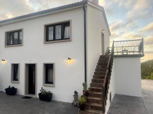 a white house with stairs and a balcony at A Casa da Moucha in Muxia