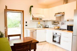 a kitchen with white cabinets and a wooden table at Stanza in Villa in mezzo al verde, vicino Bologna Via Erbosa 1B Budrio 40054 in Lupara
