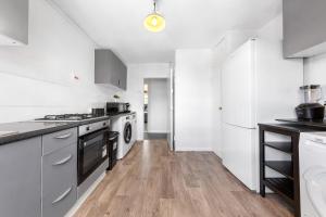a kitchen with white appliances and a wooden floor at South Stays 2 in London