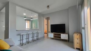a living room with a flat screen tv and stools at Apartamento Los Corrales in Rota
