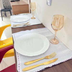a table with two white plates and two glasses at 47NV Studio Liberdade SP 300 mts Metro Japão, acomoda até 03 pessoas in Sao Paulo