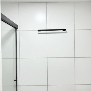 a white tile wall with a glass shower door at 47NV Studio Liberdade SP 300 mts Metro Japão, acomoda até 03 pessoas in Sao Paulo
