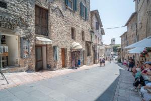 eine Straße in einem alten Steingebäude mit Menschen, die die Straße entlanggehen in der Unterkunft Monolocale San Pietro in Assisi