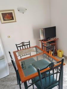 a glass table with chairs and a television in a room at Apartman Ferri 3 in Vrbanj