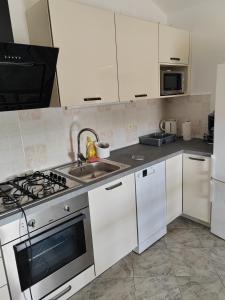 a kitchen with white cabinets and a sink and a stove at Apartman Ferri 3 in Vrbanj